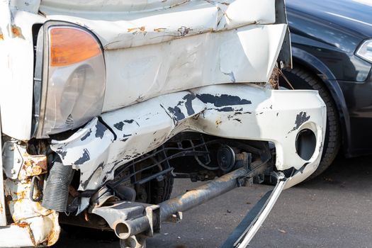 Crashed Car close-up. The front of the car is light gray, badly damaged and accidentally smashed on the road. Insurance case.