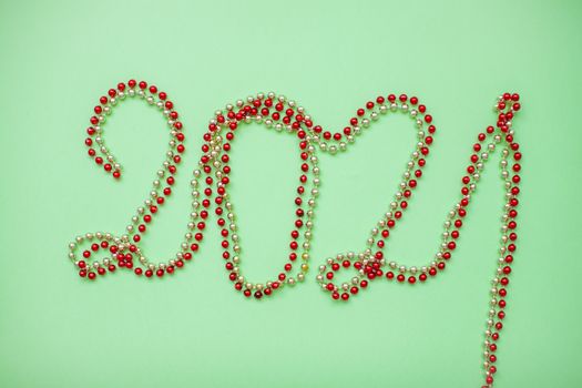 Happy New year 2021 celebration. Inscription 2021 from gold and red shiny new year beads on a green background