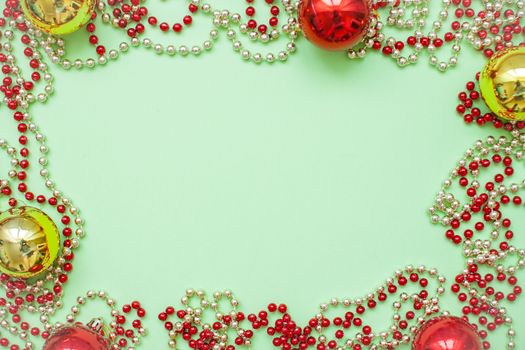 christmas frame of gold and red balls and beads on a green background
