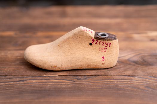 Leather samples for shoes and wooden shoe last on dark wooden table. Designer furniture clothes. Shoe maker workspace.