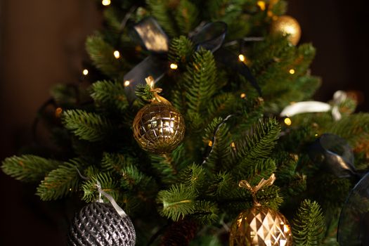 Close-up of a Christmas tree decorated with gold balls and blue bows. Christmas holiday concept. Free space for text