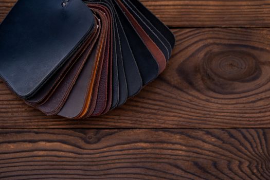 Leather samples for shoes on dark wooden table. Designer furniture clothes.