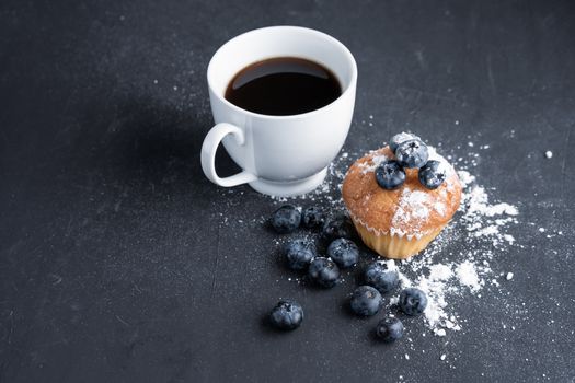 Blueberry antioxidant organic superfood and sweet muffin with cup of coffe Concept for healthy eating and dieting nutrition Top view on dark black background