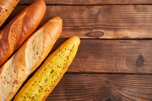 Three crispy french baguettes lie on an old wooden table with free space for text baguettes in assortment with sesame seeds Classic french national pastries Copy space Concept for menu or advertising
