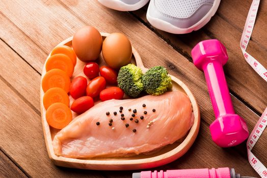 Top view of Raw chicken breasts fillets no boneless with spices in heart plate wood and sport or athlete's equipment dumbbell
running shoes on wooden background, Healthy lifestyle diet food concept