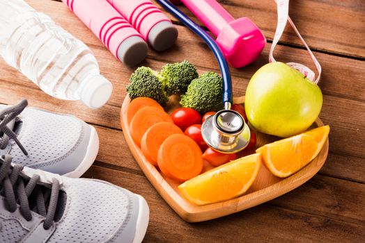 Top view of fresh fruits and vegetables in heart plate wood (apple, carrot, tomato, orange, broccoli) and sports equipment and doctor stethoscope on wooden table, Healthy lifestyle diet food concept