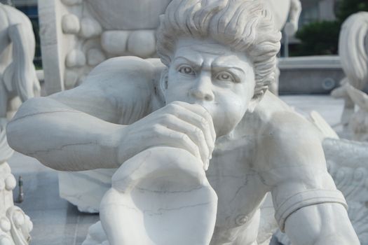 sculpture of classical water god blowing conch shell - ancient natural trumpet. Stone sculpture of a Triton, blowing on his conch shell trumpet.