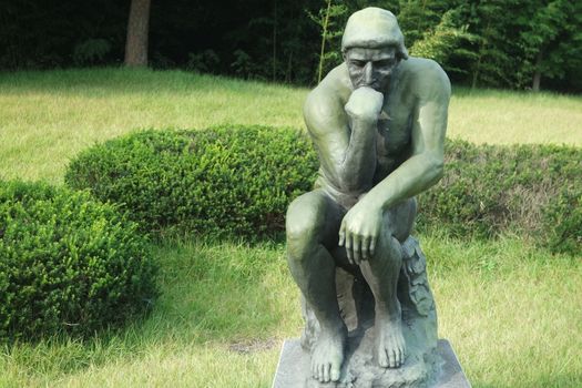 CHUNCHEON, SOUTH KOREA- JANUARY-10, 2019: Green statue of thinker Auguste Rodin, setting naked on a rock in a public park