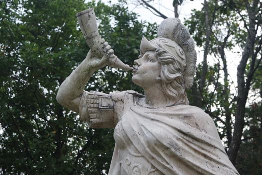 sculpture of classical water god blowing conch shell - ancient natural trumpet. Stone sculpture of a Triton, blowing on his conch shell trumpet.