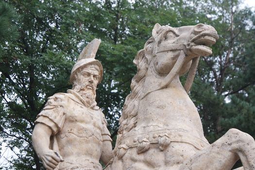 Statue made of white stone marble of an ancient famous soldier riding on the horse- White marble statue of an ancient man holding a scroll and riding a horse