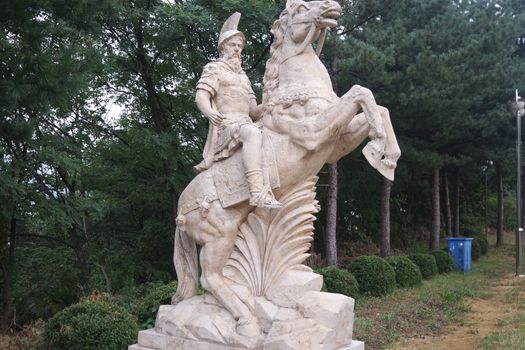 Statue made of white stone marble of an ancient famous soldier riding on the horse- White marble statue of an ancient man holding a scroll and riding a horse