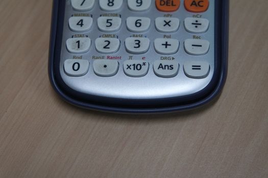 Calculator with colored keys or buttons isolated on a wooden background