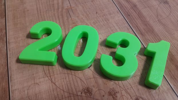 Plastic colored alphabets making words 2031 are placed on a wooden floor. These plastic letters can be used for teaching kids.