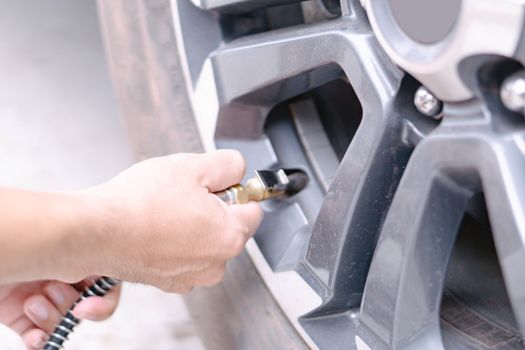 Close up man hand holding mechanic inflating tire and checking air pressure with gauge pressure in service station