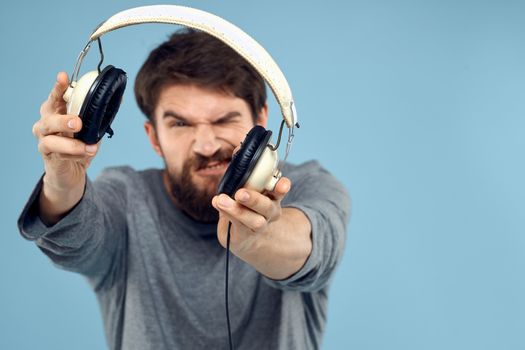 Man with headphones in hands music emotion technology lifestyle fun blue background close-up. High quality photo