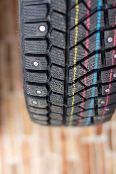 New, black winter car tires with spikes. Safe driving, preparing for winter. Tires with yellow, blue and red stripes