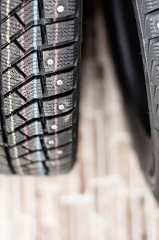 New, black winter car tires with spikes. Safe driving, preparing for winter. Tires with yellow, blue and red stripes