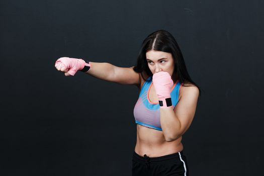 Sportsman woman boxer posing in training studio at black background