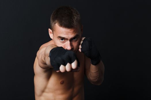 Sportsman man boxer stance hits jab at black background.