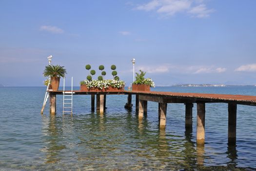 The view along a wooden pier on the banks of Lake Garda in North East Italy.