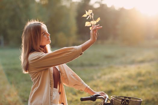 Happy active young woman riding bicycle in autumn park.