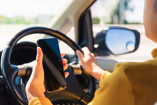 Asian woman inside a car and using a hand holding mobile smartphone blank screen while driving the car in the morning during going to work on highway, Transportation and vehicle concept