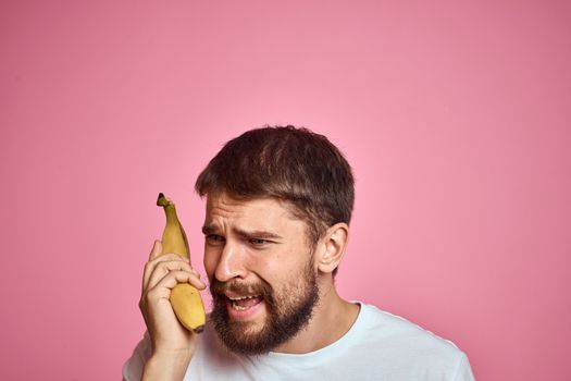 bearded man with banana in hand on pink background fun emotions model. High quality photo