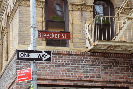 Street sign for Bleecker Street on the corner with Grove Street in New York City. Attractive brickwork on the building beyond.