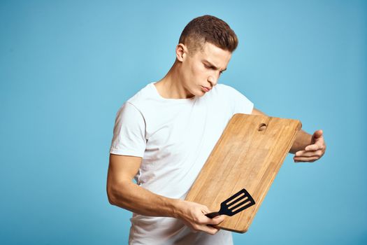 energetic guy with wooden kitchen board and spatula fun emotions. High quality photo