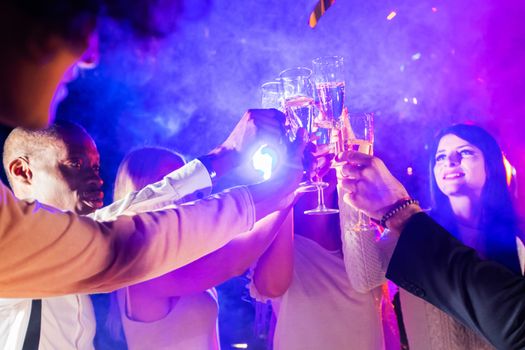 New year celebration party, holidays, nightlife and people concept - smiling friends clink glasses of champagne in night club