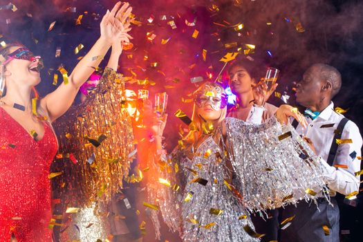 People having fun at 80s retro style party. People wearing costumes drinking champagne and dancing on dancefloor at nightclub in golden confetti