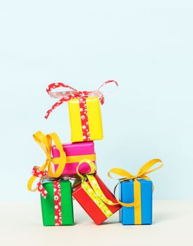 Five colorful gift boxes stacked on a pastel background. Front view.