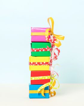 Five colorful gift boxes stacked on a pastel background. Front view.