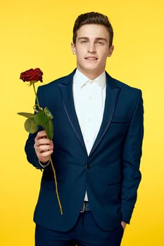 A man in a classic suit with a red rose on a yellow background. High quality photo