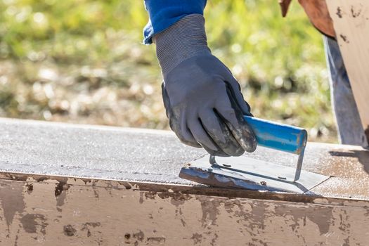 Construction Worker Using Hand Groover On Wet Cement Forming Coping Around New Pool.