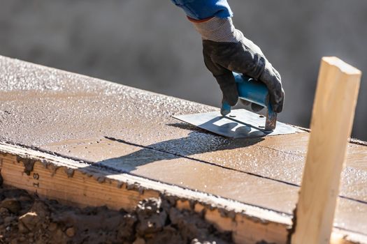 Construction Worker Using Hand Groover On Wet Cement Forming Coping Around New Pool.