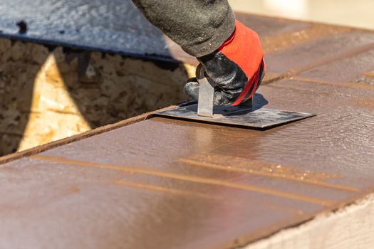 Construction Worker Using Hand Groover On Wet Cement Forming Coping Around New Pool.