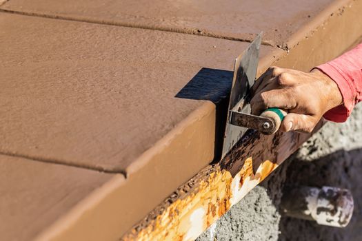 Construction Worker Using Stainless Steel Edger On Wet Cement Forming Coping Around New Pool.