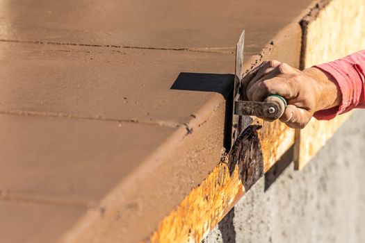 Construction Worker Using Stainless Steel Edger On Wet Cement Forming Coping Around New Pool.