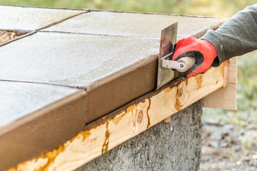 Construction Worker Using Stainless Steel Edger On Wet Cement Forming Coping Around New Pool.