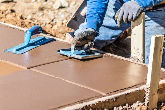 Construction Worker Using Hand Groover On Wet Cement Forming Coping Around New Pool.