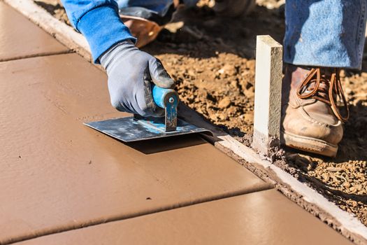 Construction Worker Using Hand Groover On Wet Cement Forming Coping Around New Pool.