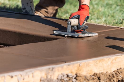 Construction Worker Using Hand Groover On Wet Cement Forming Coping Around New Pool.