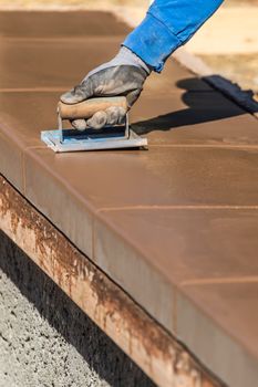 Construction Worker Using Hand Groover On Wet Cement Forming Coping Around New Pool.