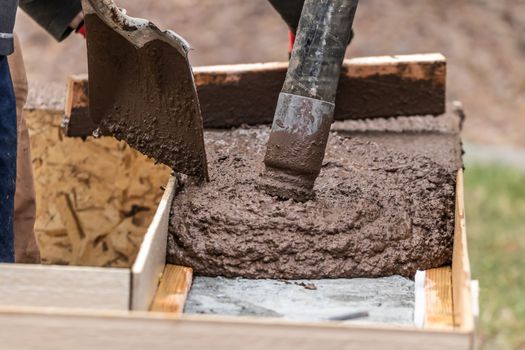 Construction Worker Leveling Wet Cement Into Wood Framing.