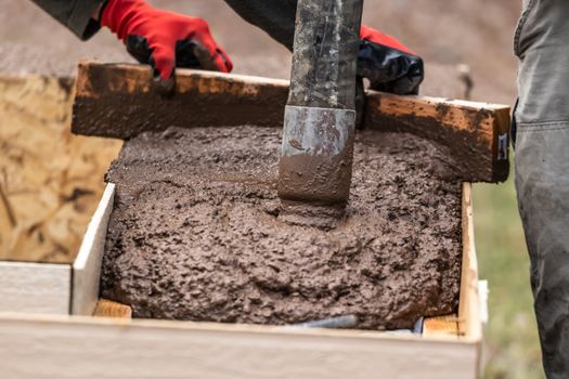 Construction Worker Leveling Wet Cement Into Wood Framing.