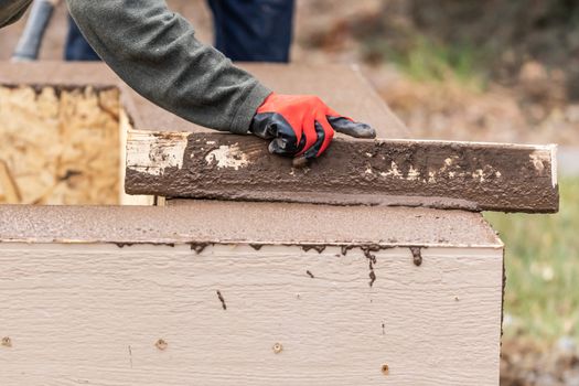 Construction Worker Leveling Wet Cement Into Wood Framing.