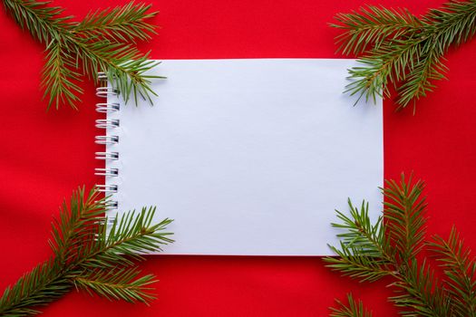 New year's composition Notepad and green spruce branches on a red background.The Concept Of Christmas.