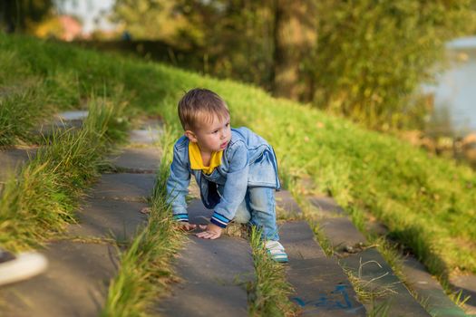 A little boy goes down the stairs in the public park one summer day.