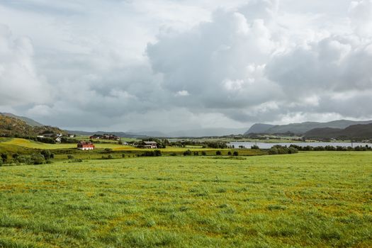 Beautiful scandinavian landscape with village, meadows, mountains and stormy sky. Lofoten islands, Norway.